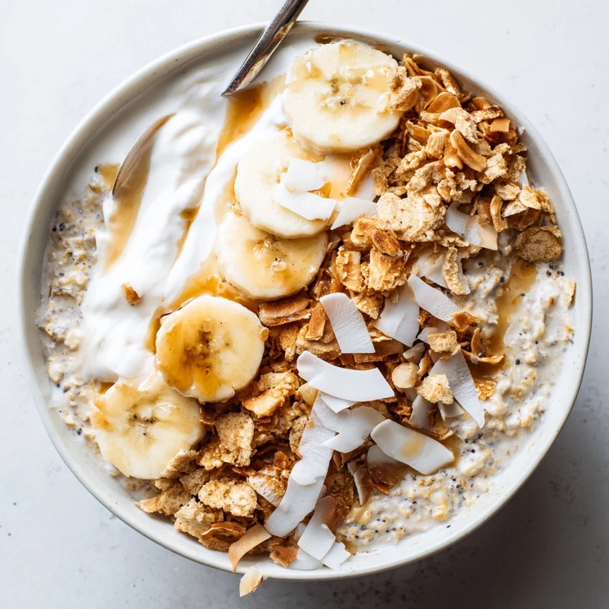 Chilled jar of Coconut Cream Pie Overnight Oats, layered with toasted coconut.