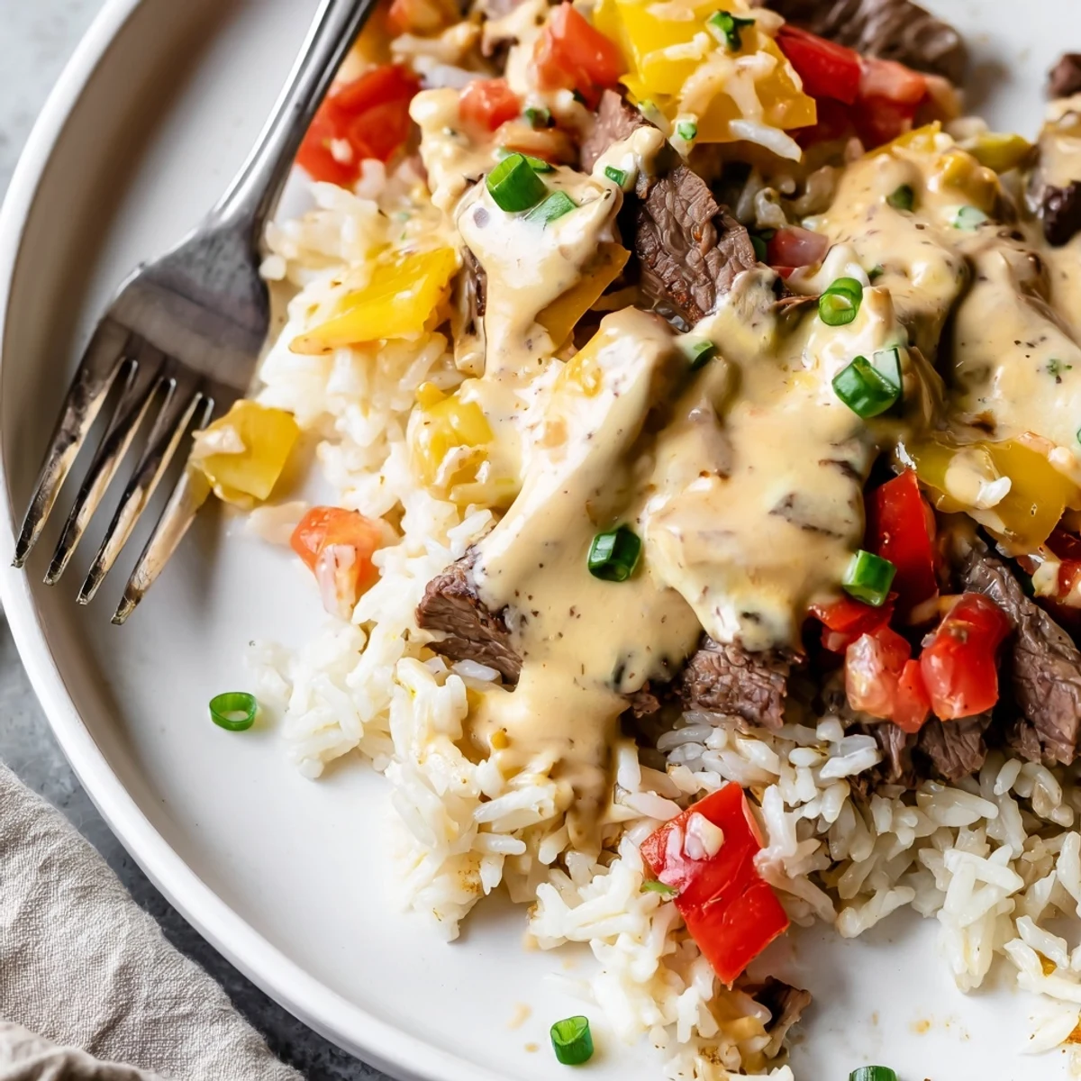 Creamy steak queso rice in a rustic bowl topped with cilantro and diced tomatoes