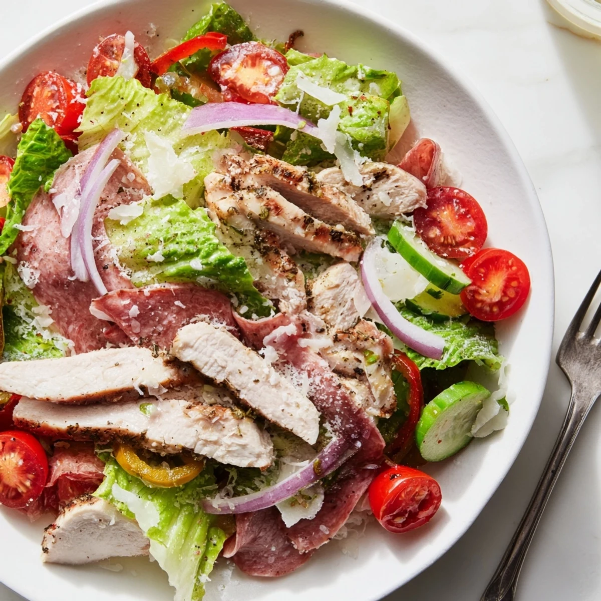 A vibrant Italian Grinder Chicken Salad topped with savory salami, provolone, and zesty vinaigrette.