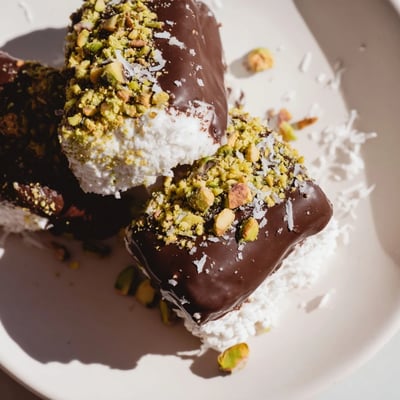 A close-up of Chocolate Dipped Marshmallows shows fluffy marshmallows dipped in smooth dark chocolate, some adorned with colorful sprinkles—perfect for a party dessert platter or homemade holiday gifts.  