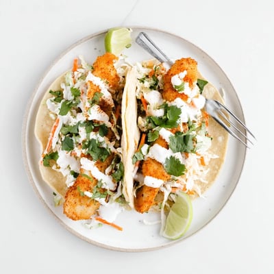 Flaky spiced baked cod nestled in warm tortillas with fresh cilantro and zesty lime crema