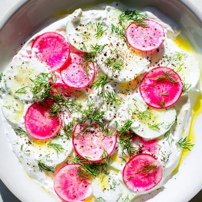 Crisp cucumbers and peppery radishes tossed in tangy dill yogurt dressing on a summer table